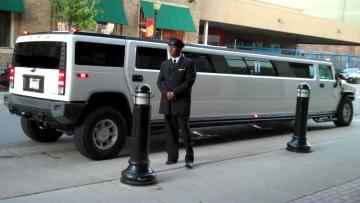 Driver waiting for his guests next to the white Hummer Limousine.